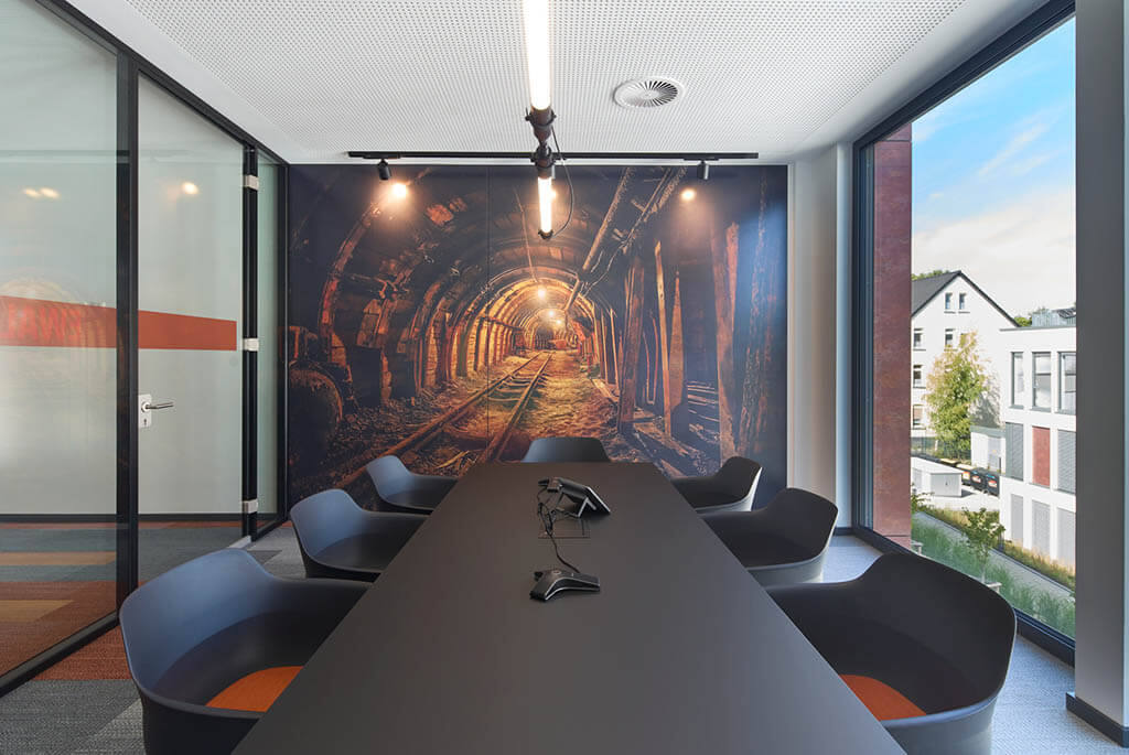 Moderner Konferenzraum mit großem Tisch und Tunnel-Wandbild im Büro